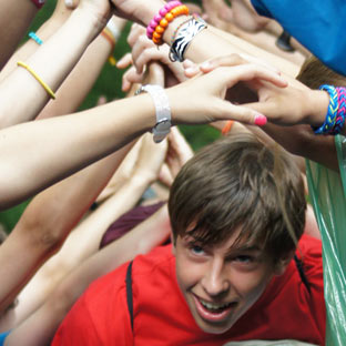 A camper passes through an arch of arms.