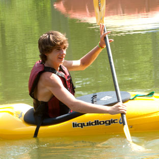 A boy pilots a kayak in a North Carolina lake
